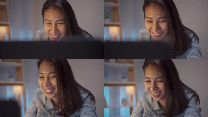 亚洲年轻女孩在家电脑工作到很晚快乐微笑成功。