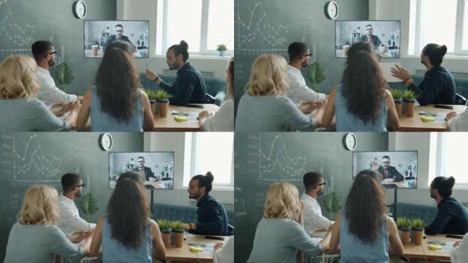 业务团队在在线视频通话中与男同事交谈，看着工作场所的数字屏幕