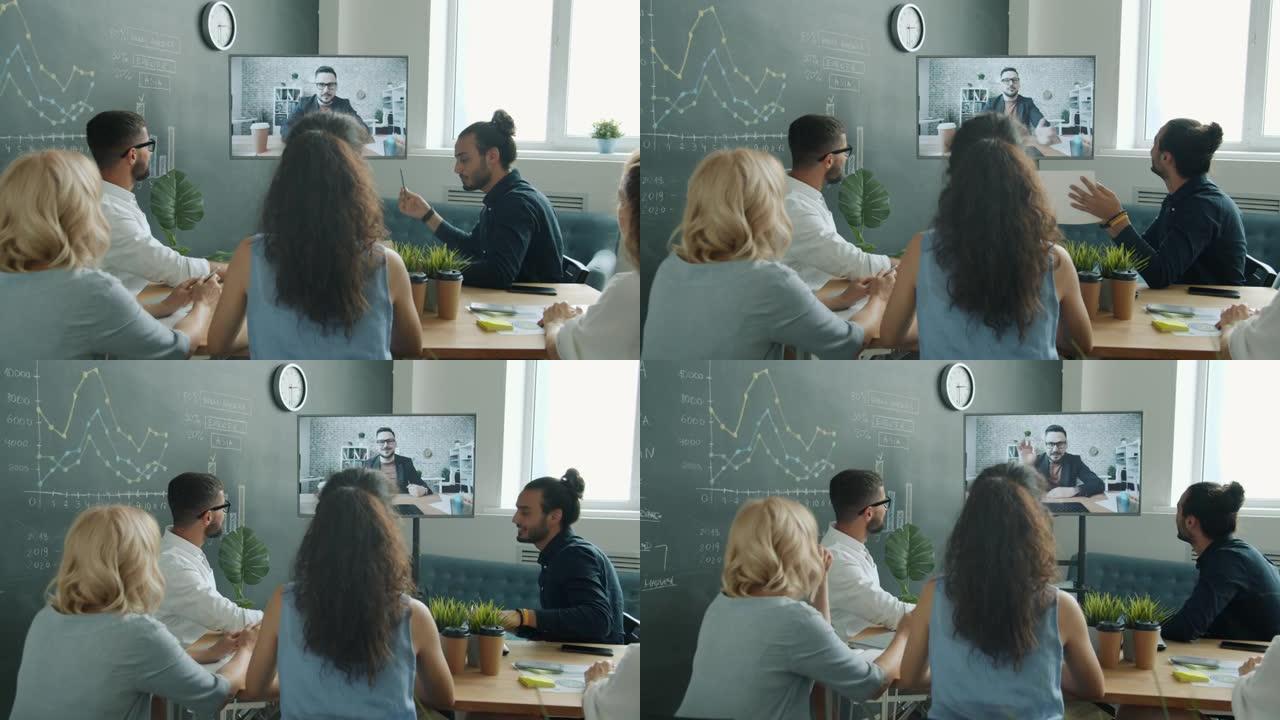 业务团队在在线视频通话中与男同事交谈，看着工作场所的数字屏幕