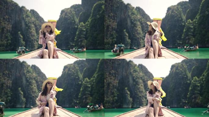 亚洲旅行妇女坐在热带石灰岩悬崖上的木长尾船上。探索和度假概念