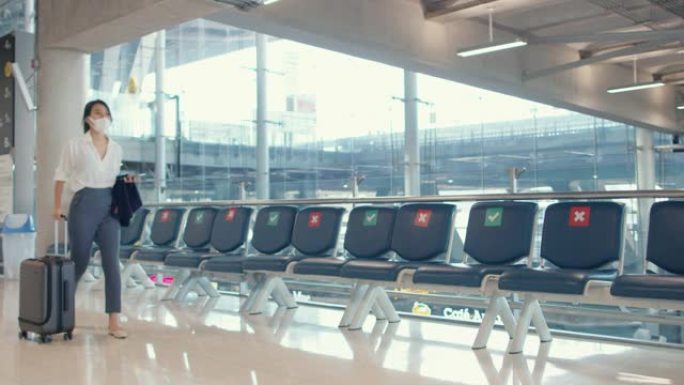 亚洲女商人使用智能手机办理登机手续，携带行李步行到机场国内航班的航站楼。