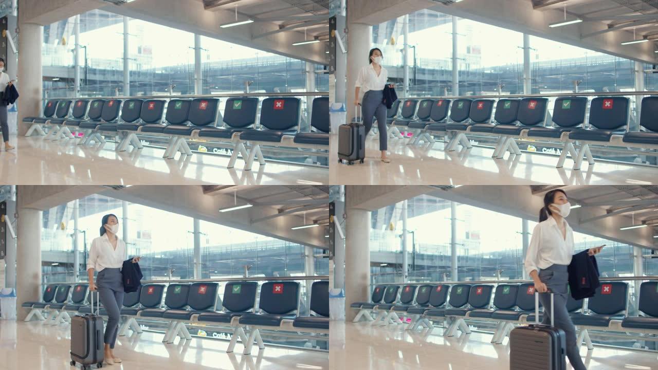 亚洲女商人使用智能手机办理登机手续，携带行李步行到机场国内航班的航站楼。