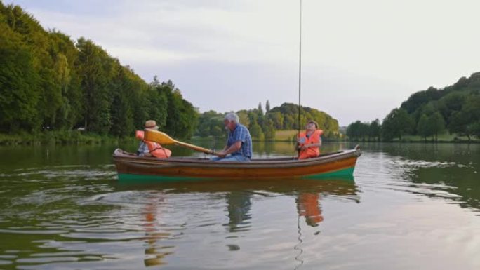 祖父和孙子坐在划船上在湖上钓鱼