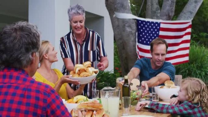 微笑的白人妇女服务家庭一起在花园庆祝餐
