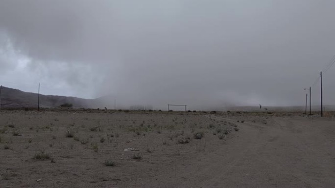 阿根廷卡塔马卡 (Catamarca) 的乡村足球场上旋转的空气柱和暴风雨的云层。