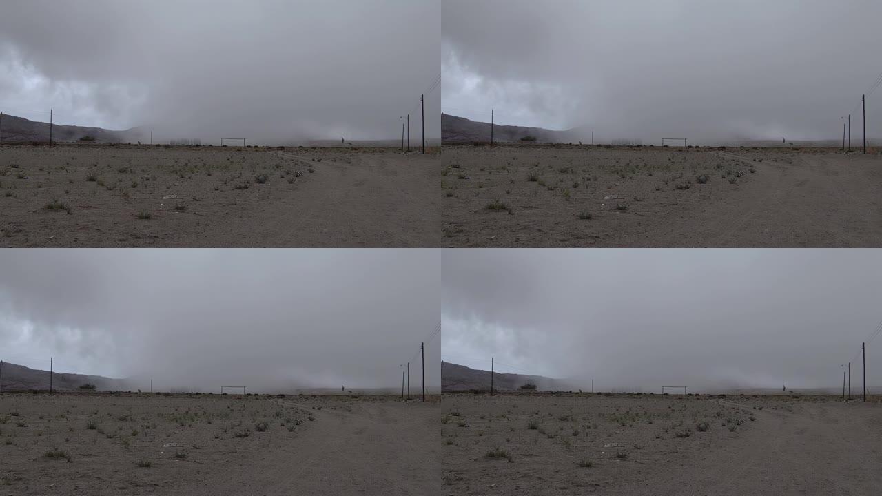 阿根廷卡塔马卡 (Catamarca) 的乡村足球场上旋转的空气柱和暴风雨的云层。