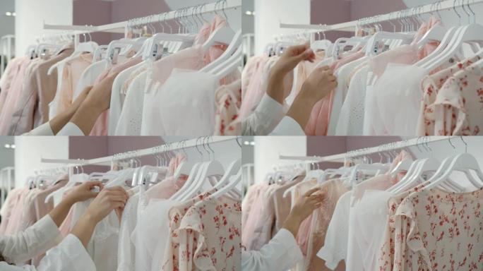 女人独自购物时，女性双手触摸衣架上的衣服的特写