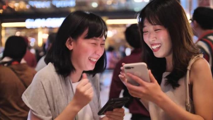 两名年轻女性朋友在城市使用智能手机