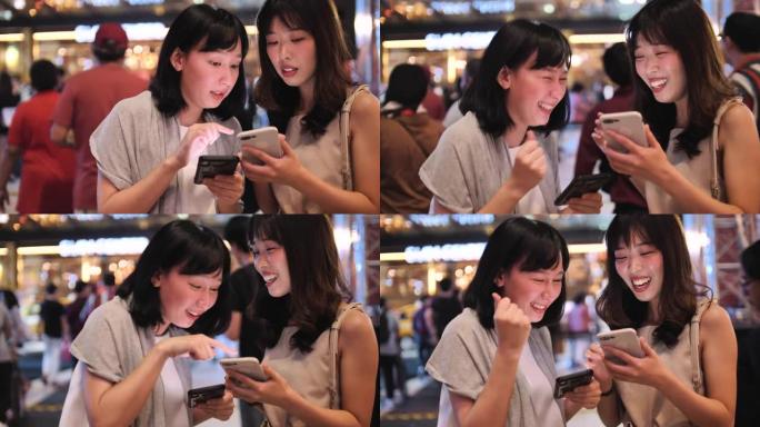两名年轻女性朋友在城市使用智能手机
