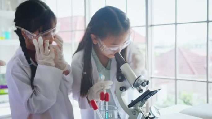 在生物学和科学课上使用显微镜与导师的特写小学生。STEM教育。