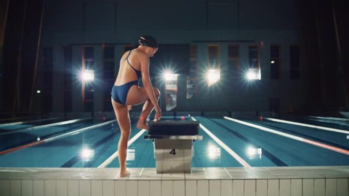 运动女游泳运动员来到起跑区跳进游泳池。职业女运动员准备赢得冠军。电影般的灯光，时尚的色彩，拍摄后的后