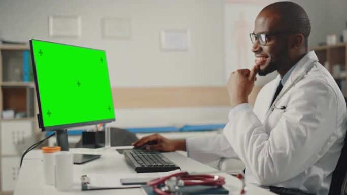 身穿白大褂的资深非裔美国男医生在绿屏模拟显示器电脑上工作。医疗保健专业人员处理测试结果和病人治疗。