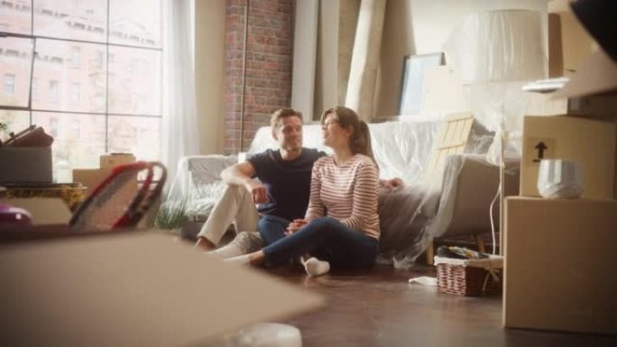 搬进来: 幸福的夫妻聊天，坐在他们新舒适住宅的客厅地板上。开朗的年轻家庭，梦想，想象美好时光，计划公