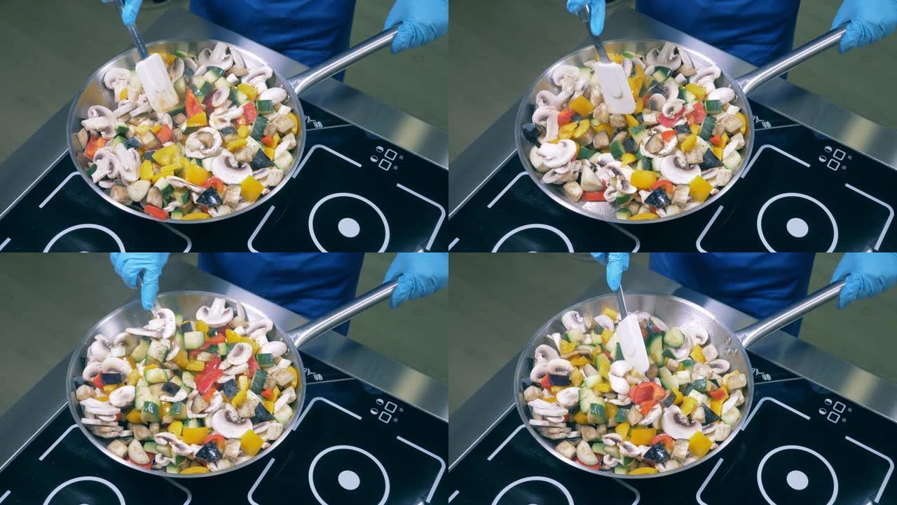 厨师用锅铲在平底锅上搅拌蔬菜和蘑菇。