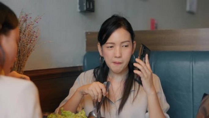 年轻女子在餐馆使用智能手机。
