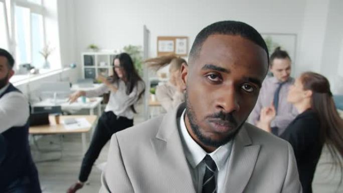 不快乐的非洲裔美国人在同事享受公司聚会时看着相机的慢动作
