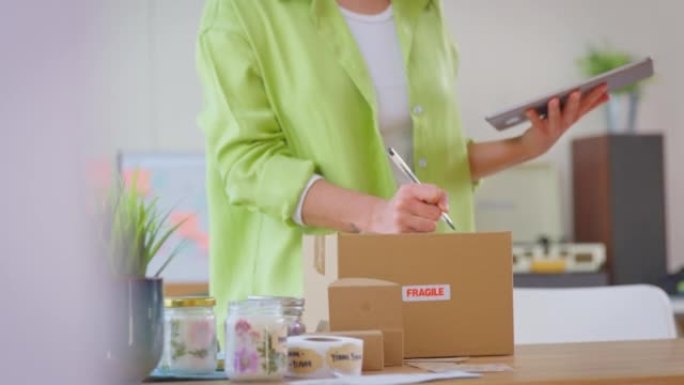 用数字平板电脑运行在线蜡烛商店的女人从家庭包装产品发货-慢动作拍摄