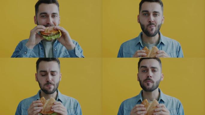 黄色背景下饥饿的年轻人吃汉堡咬咀嚼享受味道的慢动作肖像