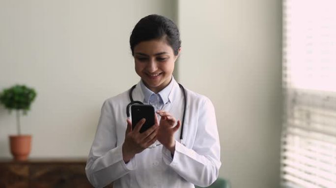 穿着制服的女医生拿着智能手机打字给病人的答案