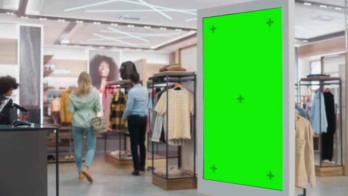 客户在服装店购物时使用带有绿屏色度键模型的落地式液晶触摸显示器。她正在检查信息，查看平面图，在线选择