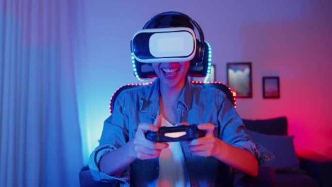 快乐的年轻亚洲女孩游戏玩家获胜者戴着虚拟现实眼镜护目镜耳机和操纵杆控制器乐趣和兴奋与在线游戏在霓虹灯