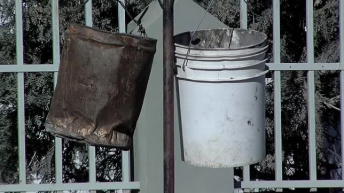生锈的水桶和旧的塑料油漆可以挂在户外的电线上。特写。