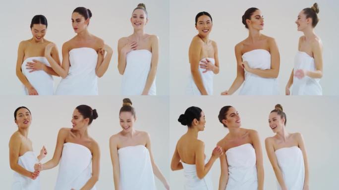 慢动作美丽的年轻微笑的女人不同的种族与完美的坚定和苗条的身体在白色浴巾跳舞和有趣的隔离在白色的背景。