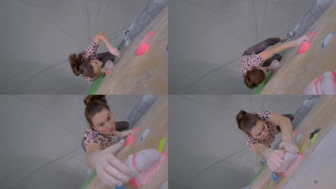 自上而下: 年轻的女登山者在室内训练设施的巨石顶上。