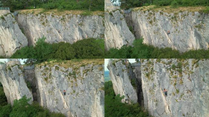 空中: 一名女运动员爬上高耸的岩壁的无人机观点