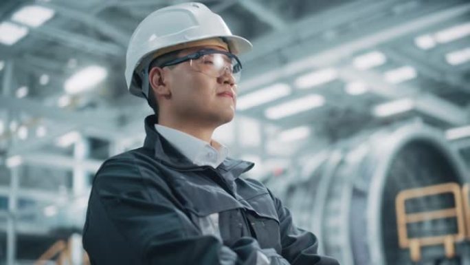 穿着安全制服，眼镜和安全帽的专业亚洲重工业工程师/工人的肖像。自信的中国工业专家站在工厂里。