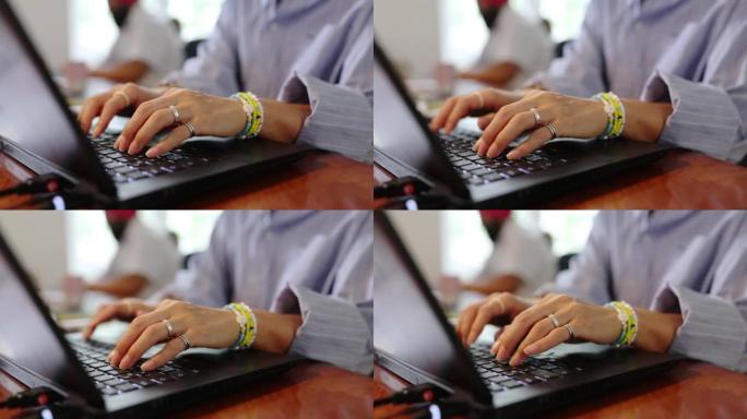 女人在办公室的桌子上在笔记本电脑上打字的特写镜头