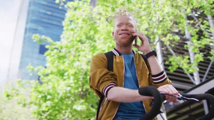快乐的白化病非裔美国男子在公园里留着辫子，自行车在智能手机上聊天