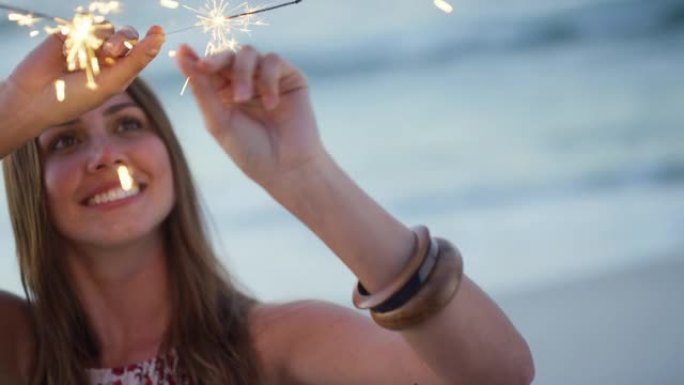 海滩，女人和烟火在澳大利亚新年晚会上庆祝夜晚，脸上充满兴奋。日落，美丽的女孩在海洋的快乐和乐趣，以欢