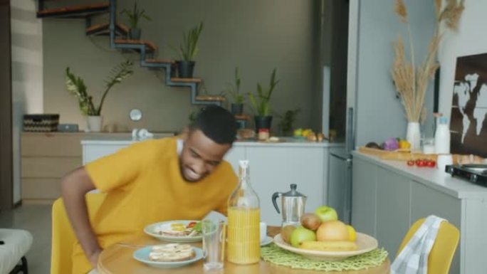快乐的非洲裔美国人在厨房享用早餐，早上使用智能手机