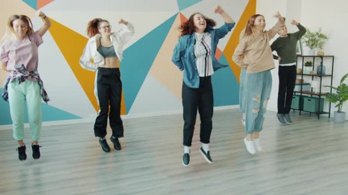 快乐青少年的慢动作在当代舞蹈工作室跳跃移动手臂跳舞