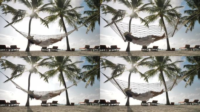 亚洲妇女在热带岛屿海滩的吊床上放松