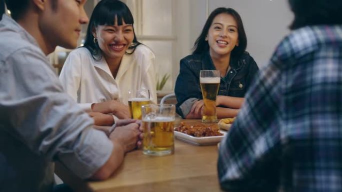 一群快乐的旅游年轻亚洲朋友喝酒精啤酒，开怀大笑，在考山路夜总会享受聚会。