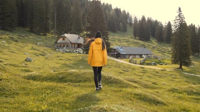 慢动作徒步旅行者穿过草地走向小屋