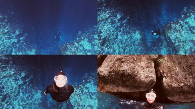 水下拍摄的女性潜水员正在探索具有生动海洋生物的珊瑚礁墙。