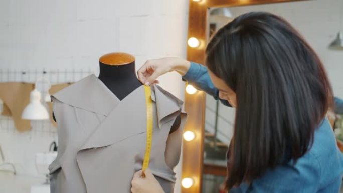 年轻女子在裁缝假人上测量面料，在工作室设计新衣服