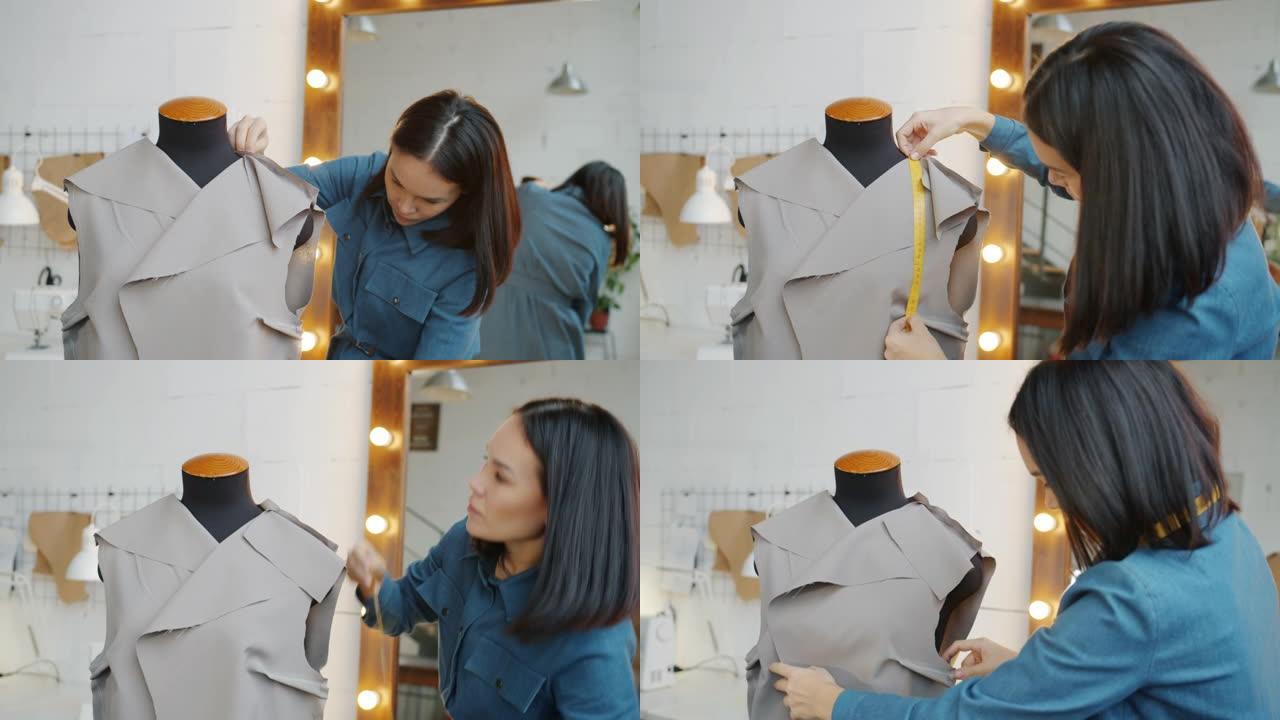 年轻女子在裁缝假人上测量面料，在工作室设计新衣服
