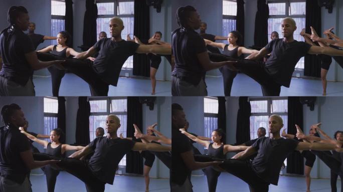 混合种族适合男性现代舞者在舞蹈课上伸展