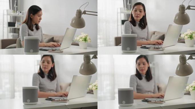 坐在办公桌前的女人在笔记本电脑上工作，在带有AI辅助功能的智能扬声器旁边回答问题