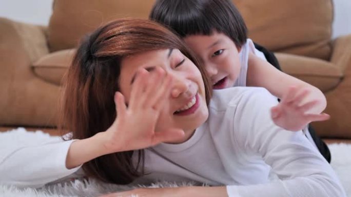 5岁的亚洲母子幸福家庭在社交距离期间在视频会议上打招呼并看着摄像机进行视频通话。家庭工作室概念。