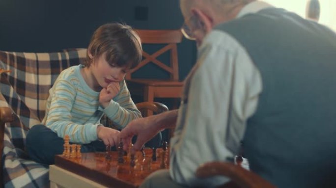 可爱的小天才，十几岁的男孩在客厅里与70多岁的祖父下棋。