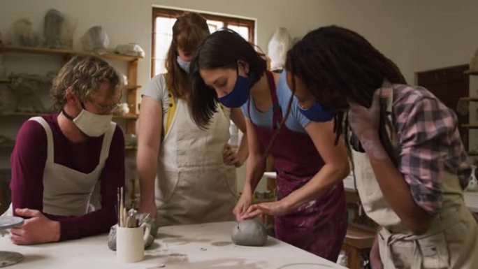 在陶器工作室，戴着口罩和围裙在粘土上工作的各种陶工