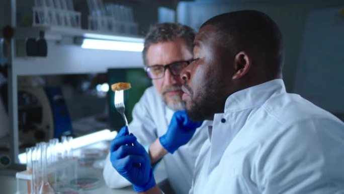 成熟的科学家看着黑人同事吃基于细胞的肉