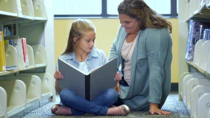 女孩和母亲坐在图书馆的地板上看书