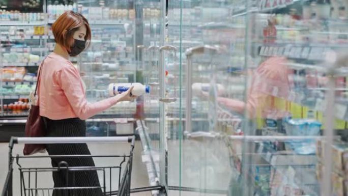 美美的亚洲女子戴着防护口罩在超市商店挑选乳制品