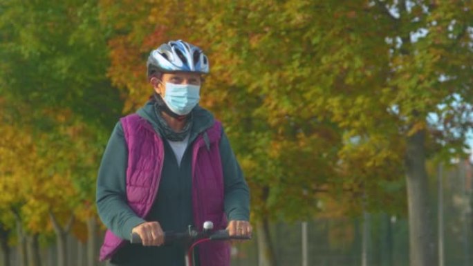 特写: 戴着口罩的快乐老妇带着电动踏板车四处行驶